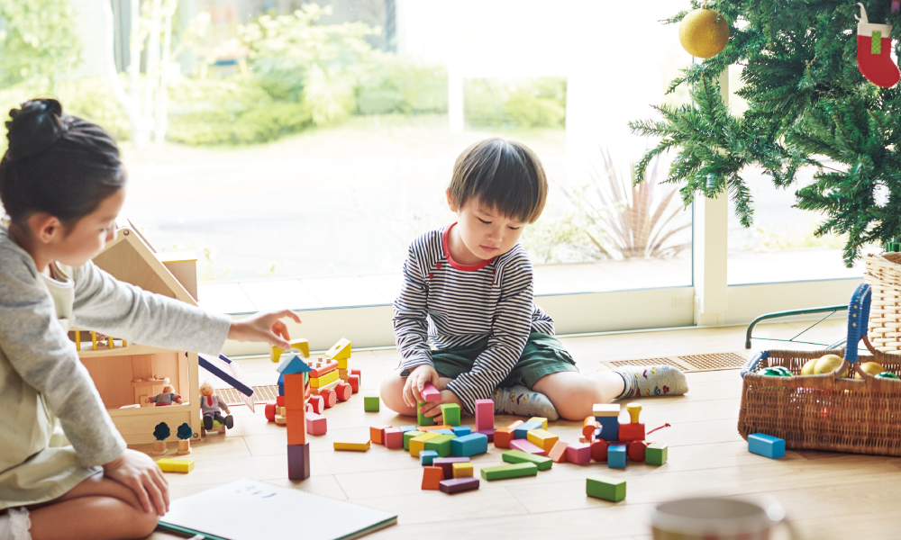 室内で積み木遊びを楽しむ兄妹の写真