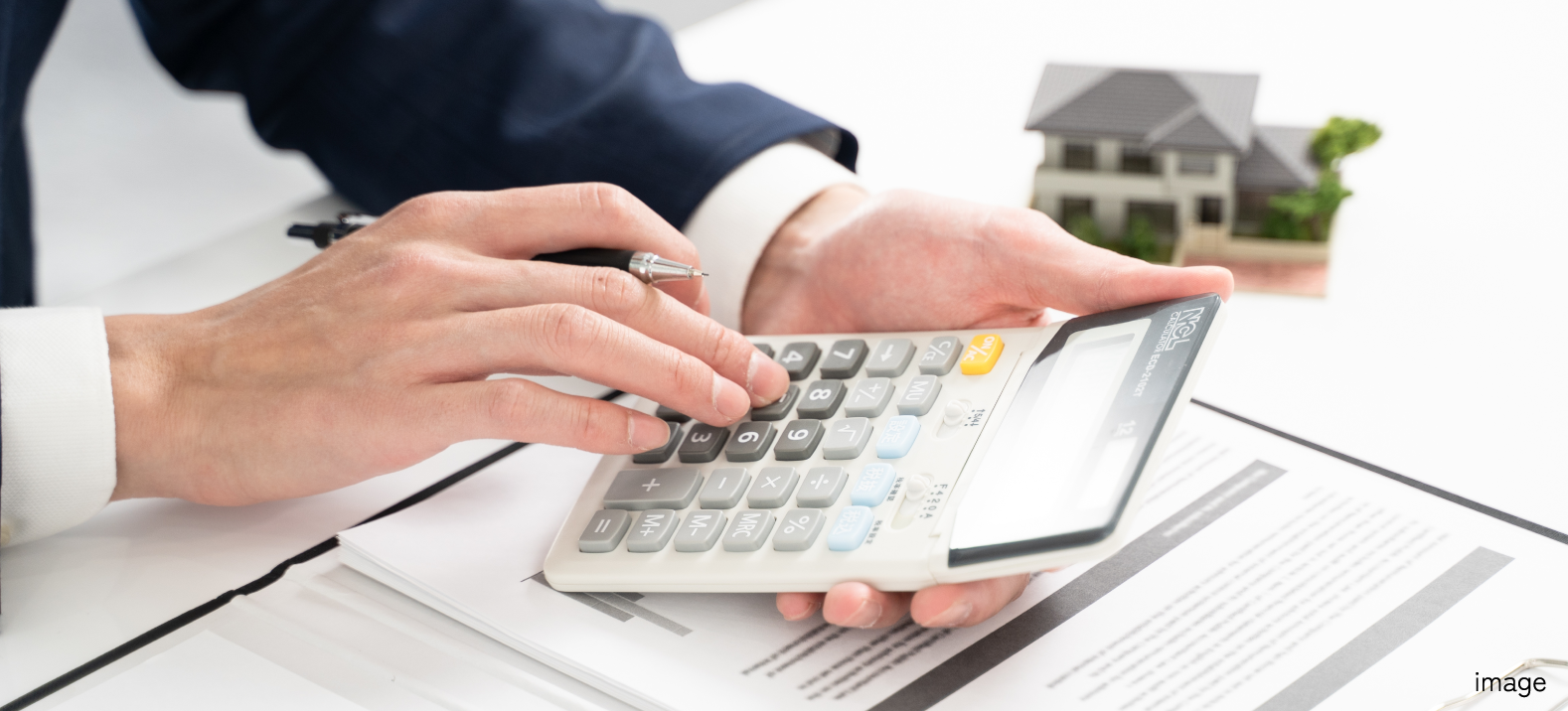 書類の上で電卓を使っている手元の写真