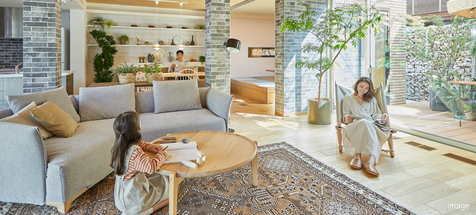 明るいリビングで家族がそれぞれくつろいで過ごしている様子の写真